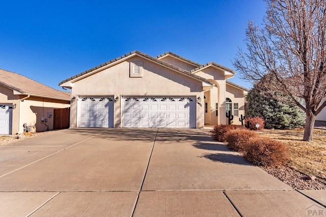 view of front facade featuring stucco siding, a garage, driveway, and a tile roof