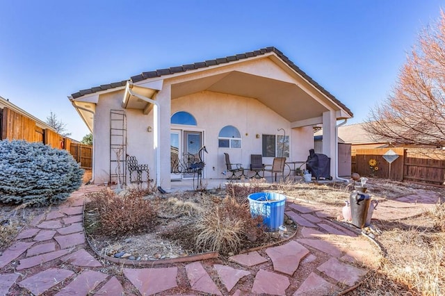 rear view of property featuring a patio area, stucco siding, and fence private yard