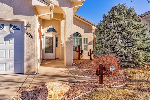 entrance to property featuring a garage and stucco siding