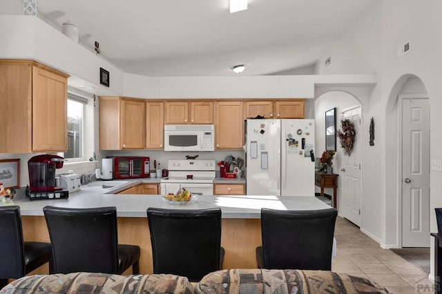 kitchen with light tile patterned floors, white appliances, a peninsula, and light countertops