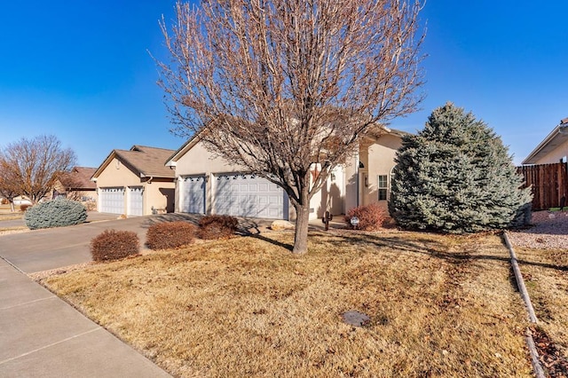 view of front of house with fence, driveway, and stucco siding