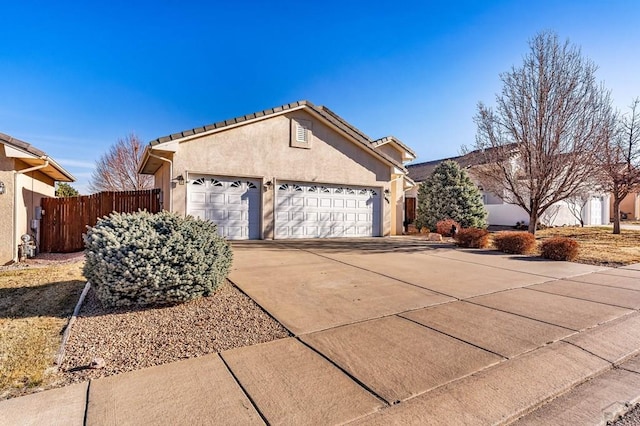 ranch-style house featuring stucco siding, a tile roof, fence, concrete driveway, and an attached garage