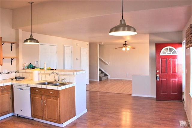 628 S Blakeland Ct, Pueblo West, CO 81007 - kitchen with white dishwasher, tile counters, a sink, a peninsula, and dark wood-type flooring