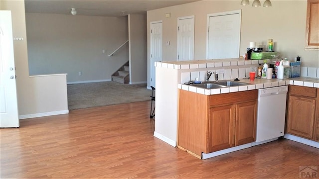 628 S Blakeland Ct, Pueblo West, CO 81007 - kitchen with white dishwasher, tile countertops, a sink, light wood-type flooring, and a peninsula