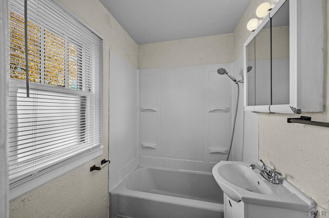 full bath with a textured wall, shower / tub combination, and vanity