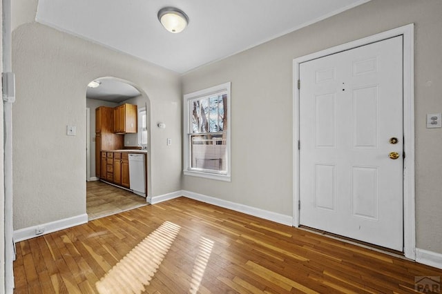 entrance foyer with baseboards, arched walkways, and wood finished floors