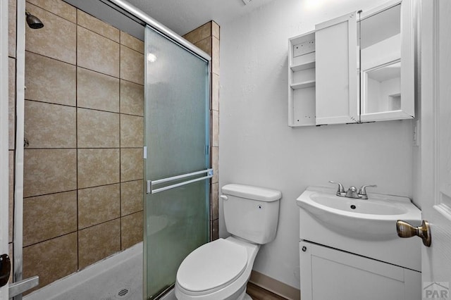 bathroom with toilet, a shower stall, and vanity