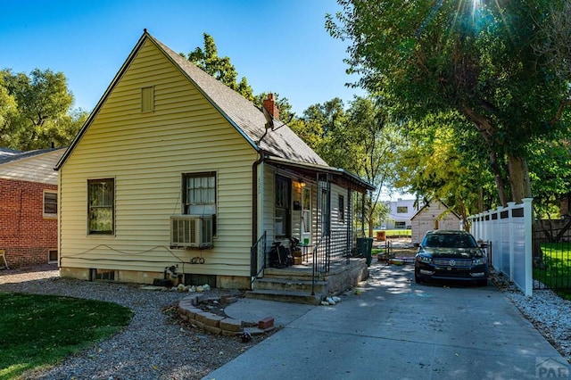 view of front of property featuring a chimney, a shingled roof, a porch, fence, and cooling unit