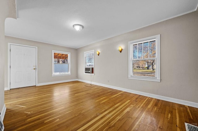 empty room with baseboards, plenty of natural light, visible vents, and wood finished floors