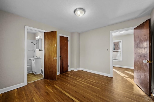 unfurnished bedroom featuring dark wood-style flooring, a closet, and baseboards