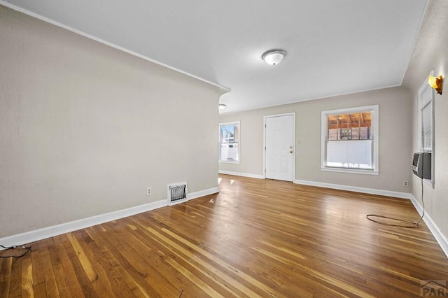 interior space featuring cooling unit, wood finished floors, visible vents, and baseboards