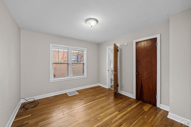 spare room with visible vents, baseboards, and wood finished floors