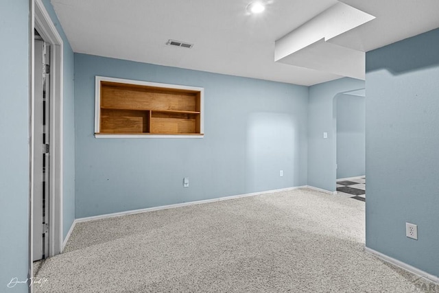 unfurnished room featuring arched walkways, carpet floors, visible vents, and baseboards