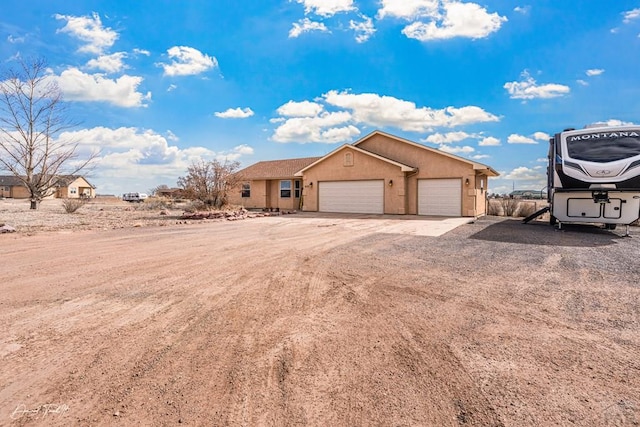 ranch-style home featuring an attached garage, driveway, and stucco siding