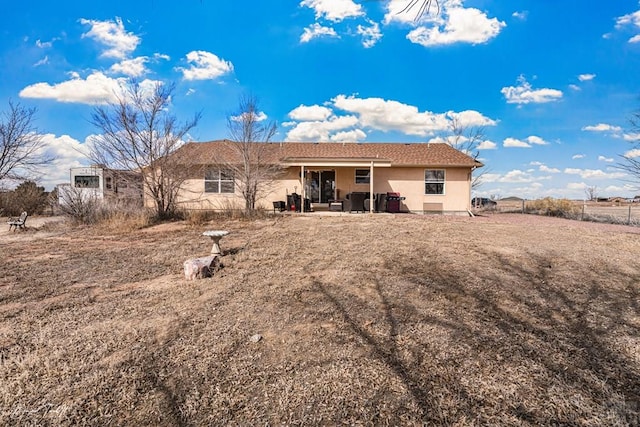 rear view of house featuring a patio, fence, and stucco siding