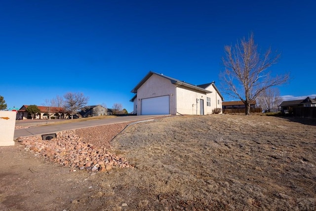 view of property exterior with a garage, driveway, and stucco siding