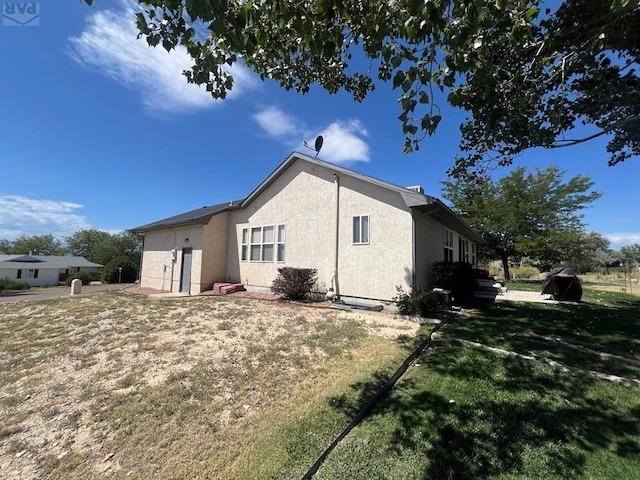 view of side of property featuring a yard and stucco siding