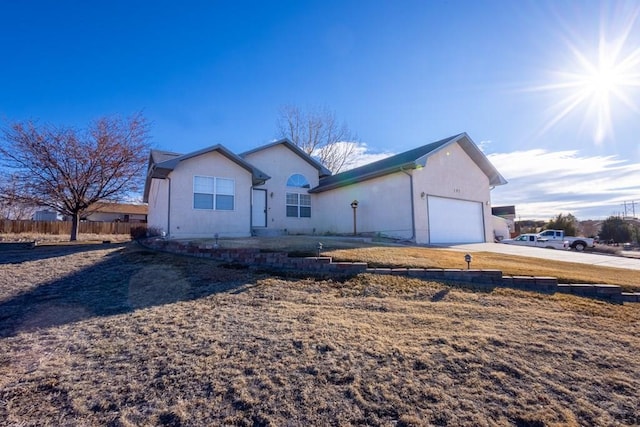 ranch-style home featuring a garage, fence, driveway, and stucco siding