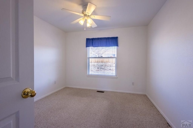 carpeted spare room featuring visible vents, a ceiling fan, and baseboards