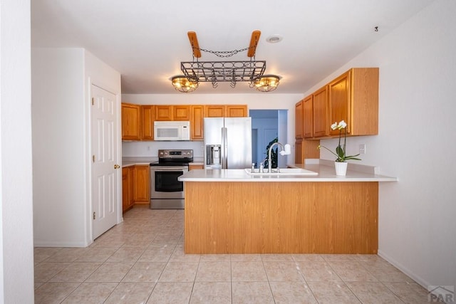 kitchen featuring a peninsula, appliances with stainless steel finishes, light countertops, and a sink