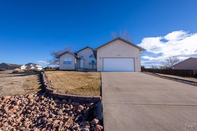 single story home featuring an attached garage, fence, concrete driveway, and stucco siding