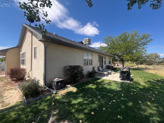 rear view of property featuring a patio, stucco siding, a lawn, entry steps, and central AC