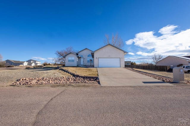 ranch-style house featuring a garage, driveway, fence, and stucco siding