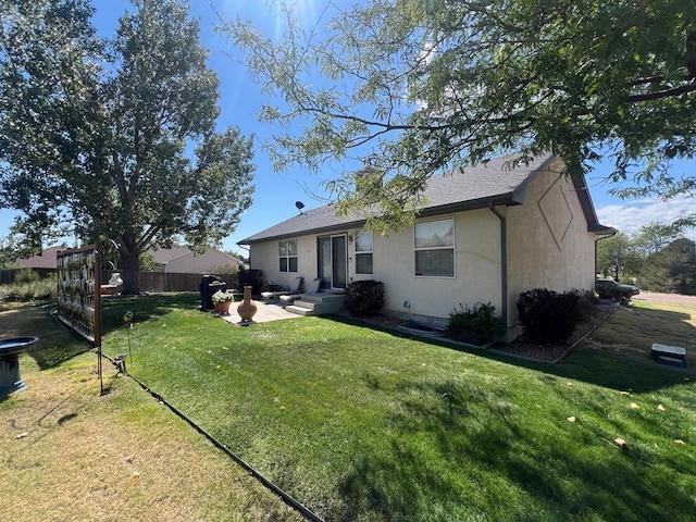 back of house featuring a yard, a patio area, fence, and stucco siding