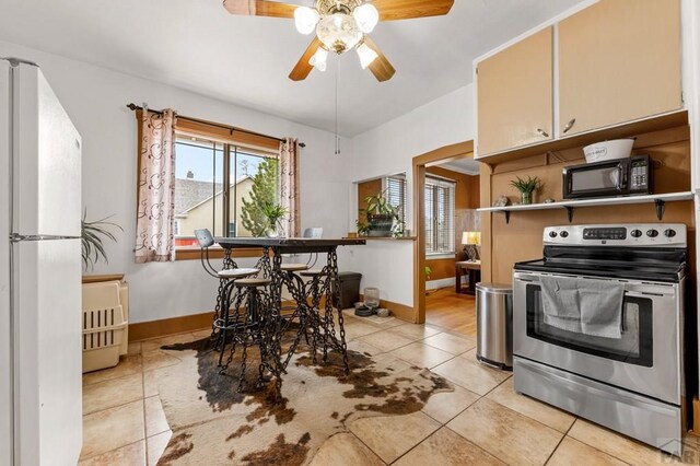 1802 E Routt Ave, Pueblo, CO 81004 - kitchen with light tile patterned flooring, a ceiling fan, black microwave, freestanding refrigerator, and stainless steel range with electric stovetop