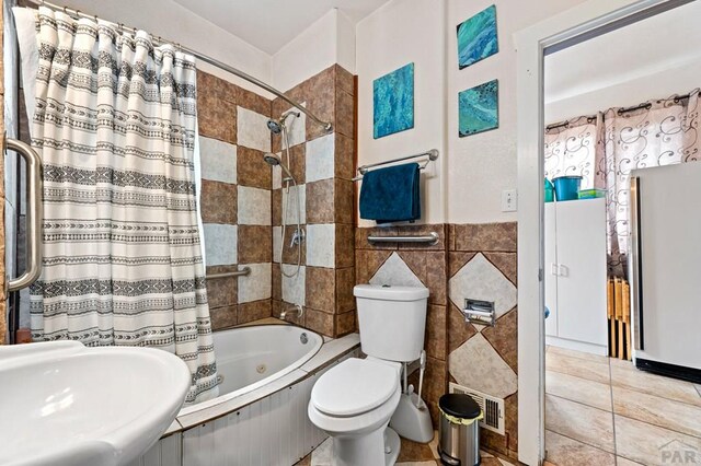 1802 E Routt Ave, Pueblo, CO 81004 - bathroom with tile patterned floors, toilet, shower / tub combo with curtain, a sink, and tile walls