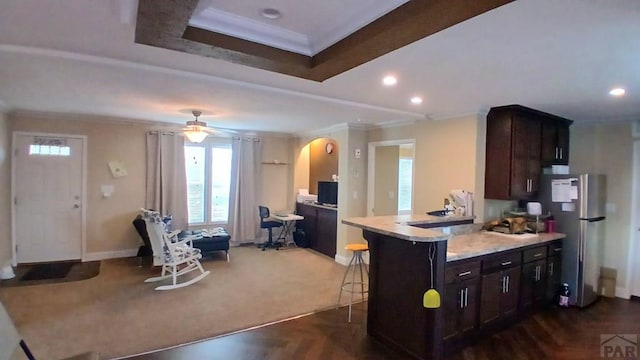 999 Fortino Blvd Unit 108, Pueblo, CO 81008 - kitchen with ornamental molding, freestanding refrigerator, plenty of natural light, a kitchen bar, and dark brown cabinets