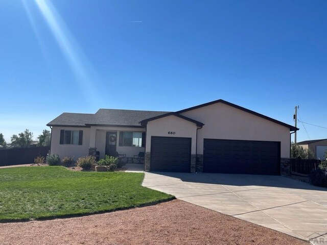 single story home with stucco siding, an attached garage, fence, stone siding, and driveway