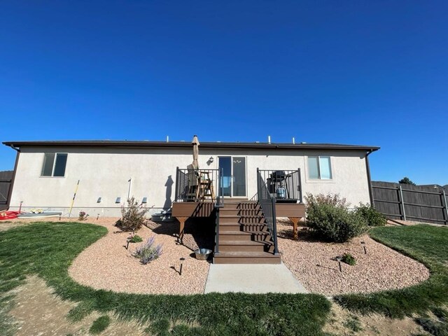 back of property featuring fence, a lawn, and stucco siding