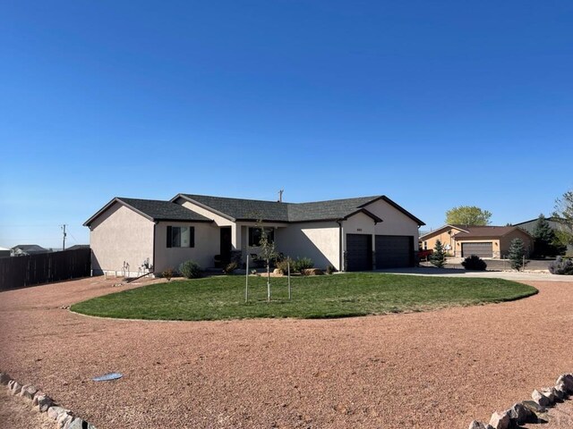 ranch-style house with driveway, an attached garage, fence, a front yard, and stucco siding