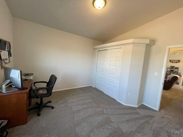 carpeted office featuring lofted ceiling and baseboards