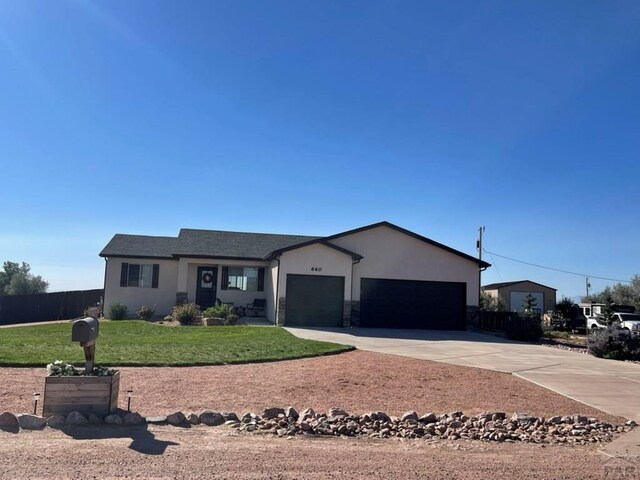 single story home with a garage, fence, concrete driveway, stucco siding, and a front lawn