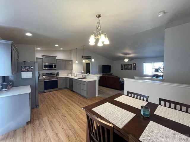 dining room with lofted ceiling, light wood-type flooring, recessed lighting, and ceiling fan with notable chandelier