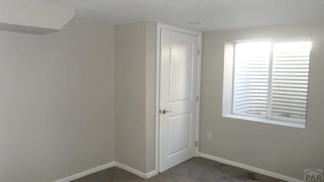 carpeted empty room featuring baseboards