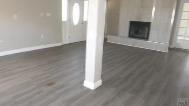 unfurnished living room featuring baseboards and dark wood finished floors