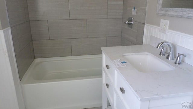full bathroom with a tub to relax in, walk in shower, a wainscoted wall, and vanity