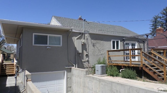 exterior space featuring stairs, a garage, stucco siding, a deck, and central AC unit