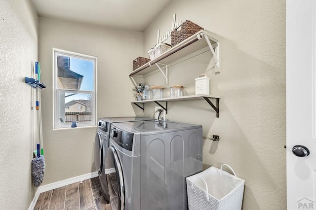 clothes washing area with dark wood-style floors, laundry area, separate washer and dryer, and baseboards