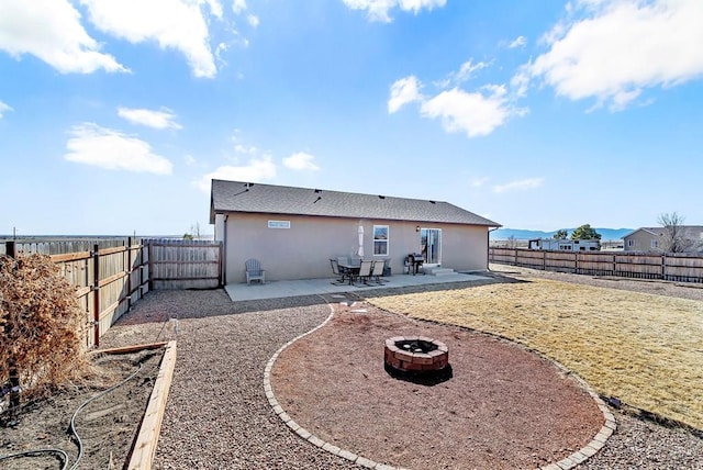 rear view of property with a patio area, a fenced backyard, a fire pit, and stucco siding