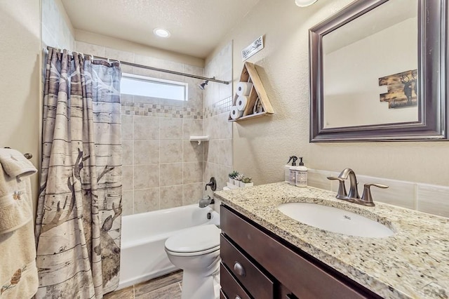 bathroom featuring shower / bath combo, a textured wall, toilet, a textured ceiling, and vanity