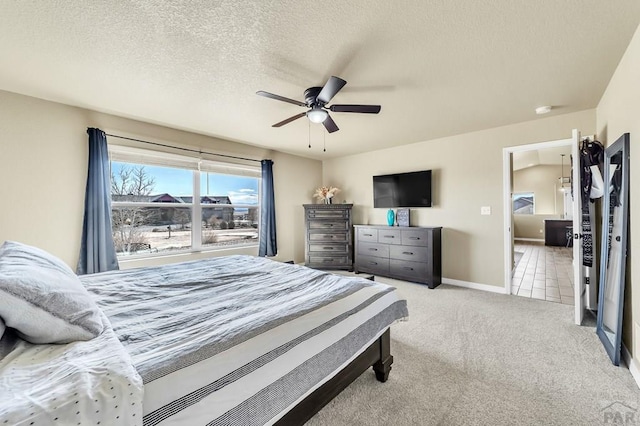 carpeted bedroom with ceiling fan, a textured ceiling, baseboards, and tile patterned floors