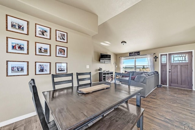 dining space with lofted ceiling, baseboards, and wood finished floors