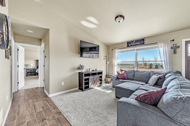 living room featuring lofted ceiling, baseboards, and wood finished floors