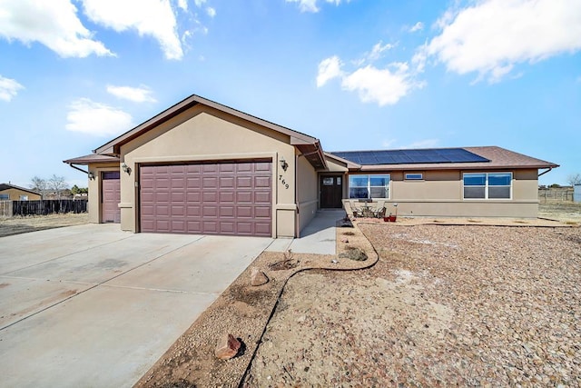 ranch-style home featuring a garage, solar panels, driveway, and stucco siding