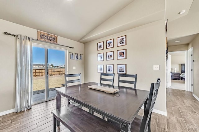 dining area with wood tiled floor, vaulted ceiling, and baseboards