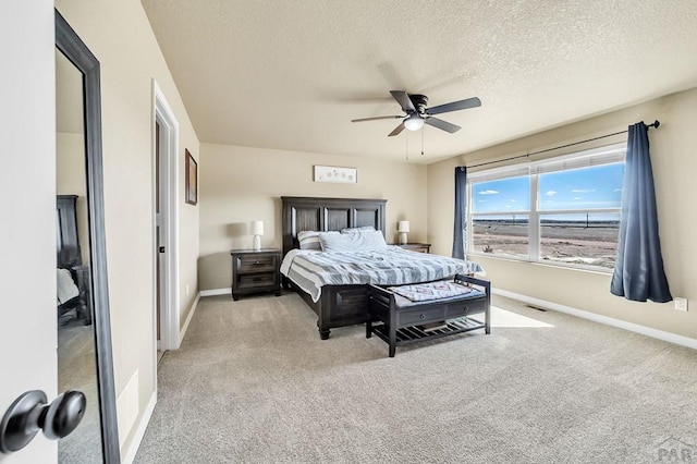 bedroom with light carpet, a textured ceiling, a ceiling fan, and baseboards